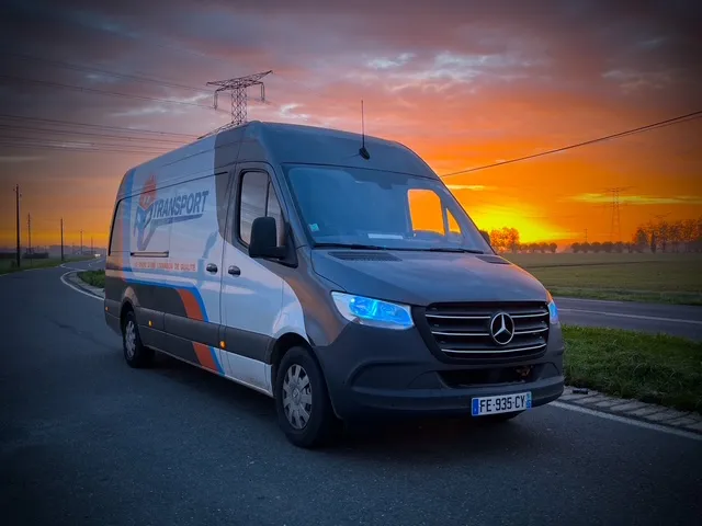 Camionnette de transport express AP Transport sur la route, illuminée par un lever de soleil saisissant. ​​